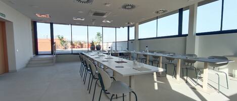 Una amplia sala de conferencias con una larga mesa, sillas y ventanas grandes.