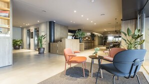 A spacious lobby with a reception desk, seating area, and a kitchen in the background. - Hotel Terrassa Confort (Terrassa)