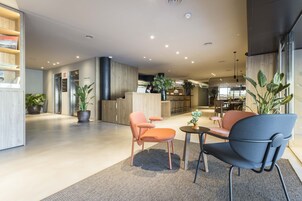 Un vestíbulo amplio con una mesa de recepción, zona de estar y una cocina al fondo.