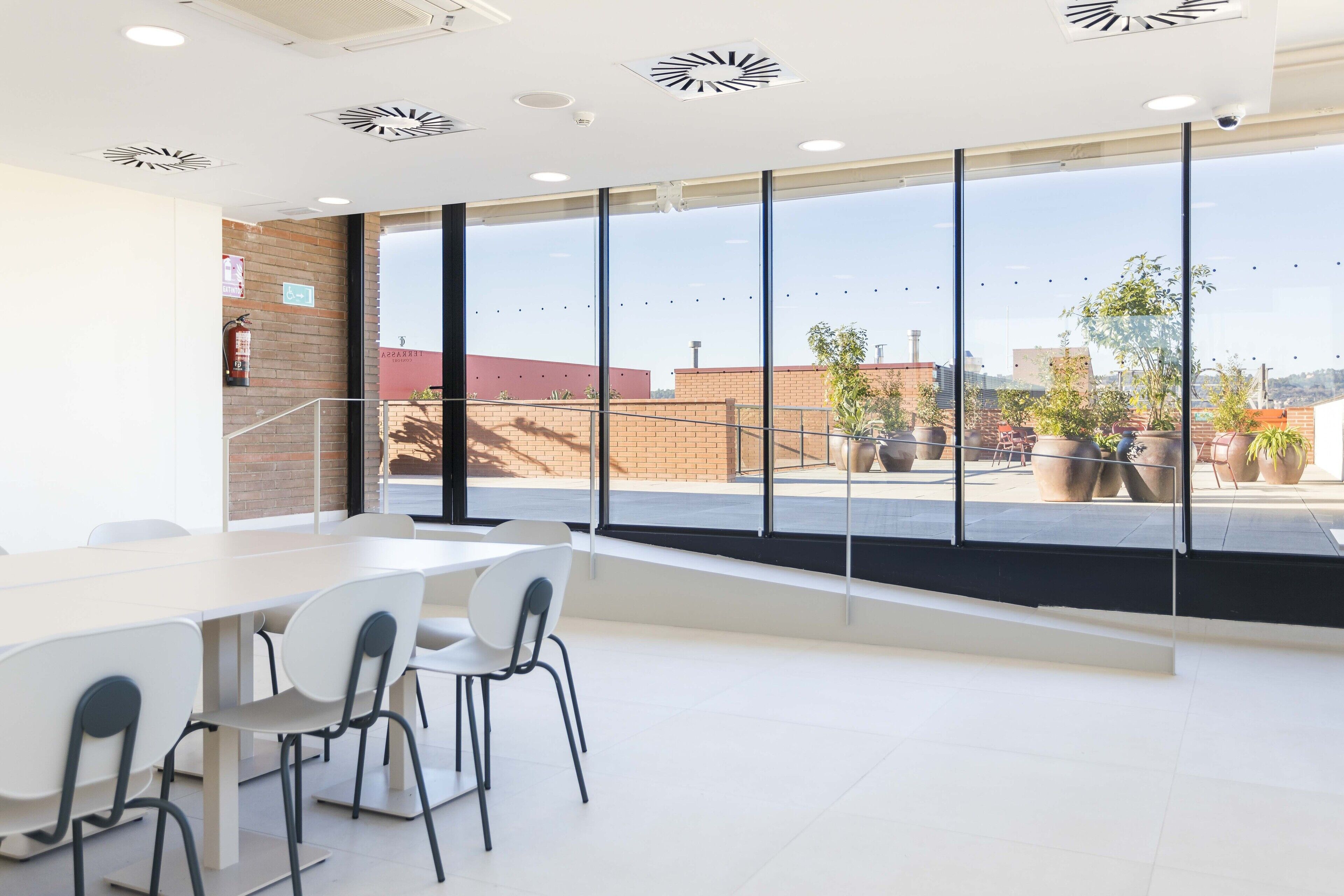 A modern interior with a large window, white chairs, and a white table.