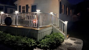 Une maison miniature dotée d’un porche, d’une balustrade et d’un petit jardin.