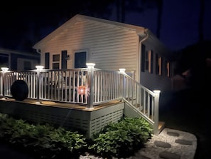 A model house with a porch, railing, and a small garden area.
