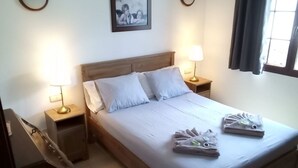 A neatly made bed with pillows, a bedside lamp, and folded towels on a wooden bed frame. - Looking for a vacation in the sun? Book Casa Morgana now! (Playa Blanca)