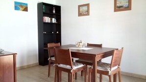A dining area with a wooden table and chairs, a bookshelf, and two framed pictures on the wall. - Looking for a vacation in the sun? Book Casa Morgana now! (Playa Blanca)