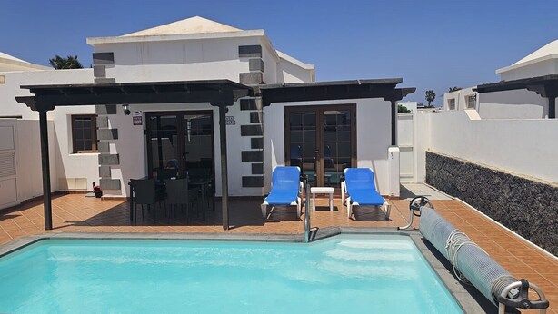 A pool area with two lounge chairs, a covered seating area, and a grill. - Looking for a vacation in the sun? Book Casa Morgana now! (Playa Blanca)