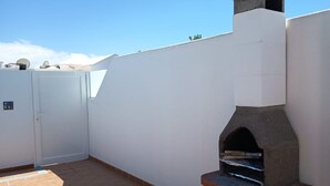 A rooftop patio with a stone-built oven, a white wall, and a door. - Looking for a vacation in the sun? Book Casa Morgana now! (Playa Blanca)