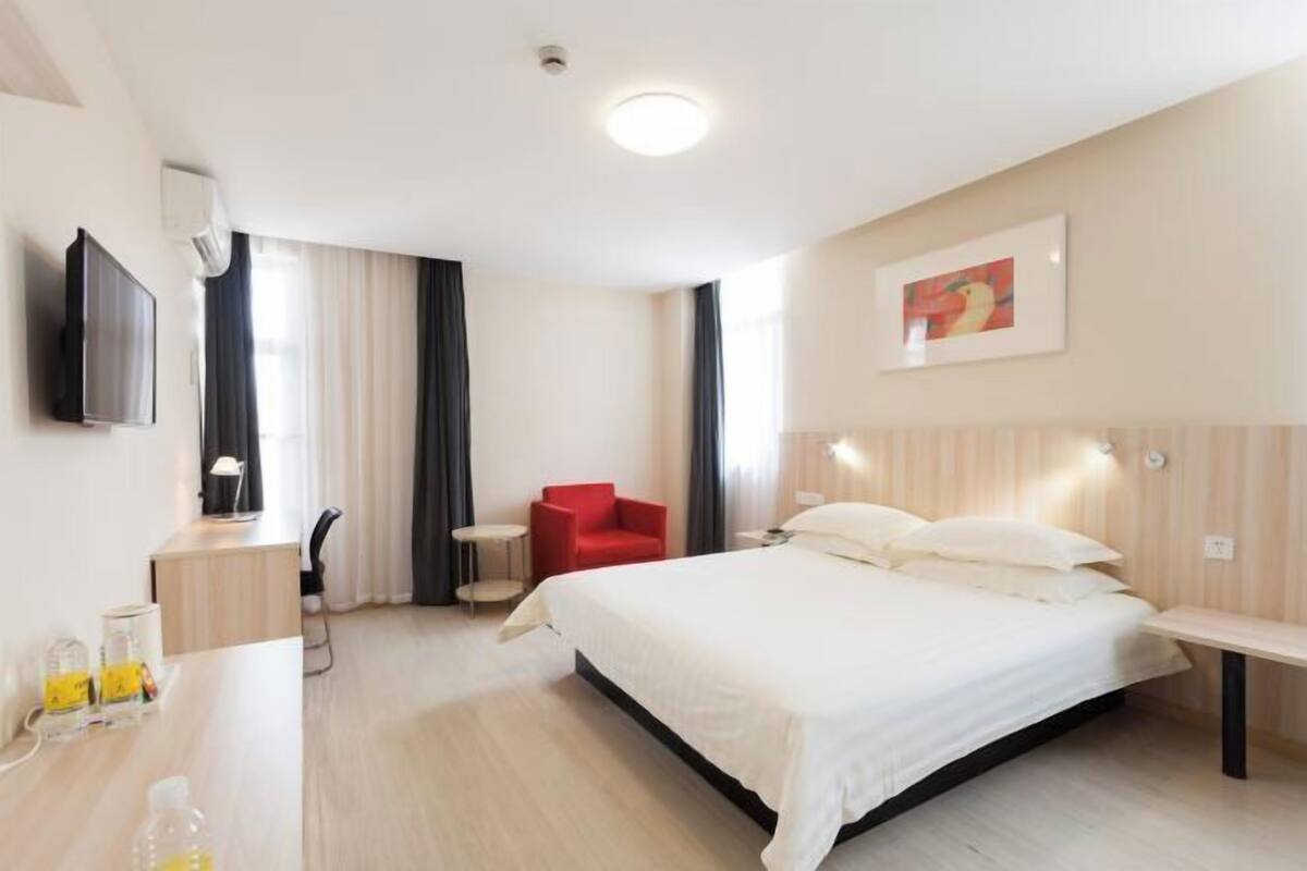 Une chambre d’hôtel avec un lit, un bureau, une chaise, une télévision et un tableau au mur.