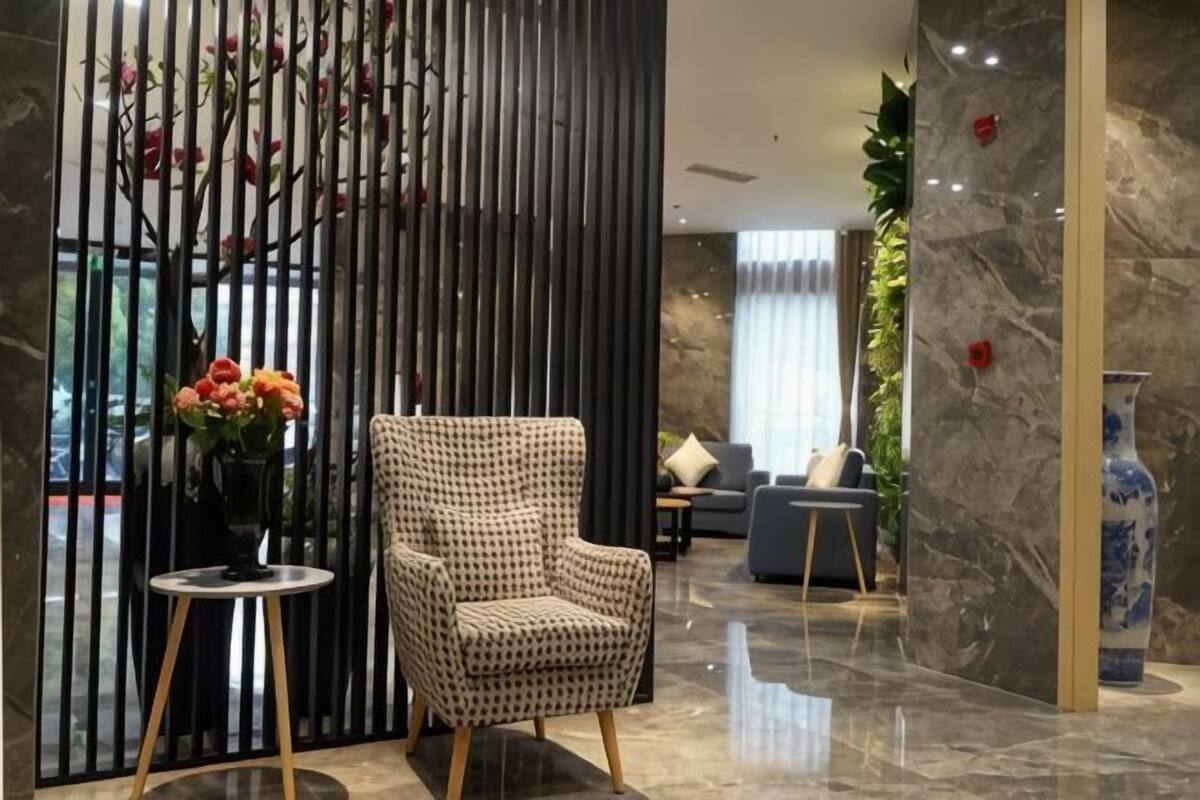 Un hall d’entrée moderne avec un fauteuil à motifs, un vase de fleurs et un mur décoratif.