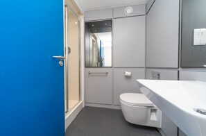 A modern bathroom with a white toilet, a sink, and a shower area. - JOIVY Affordable 3,4,5 and 12 bed private flats next to Royal Mile - Adults only (Edinburgh)