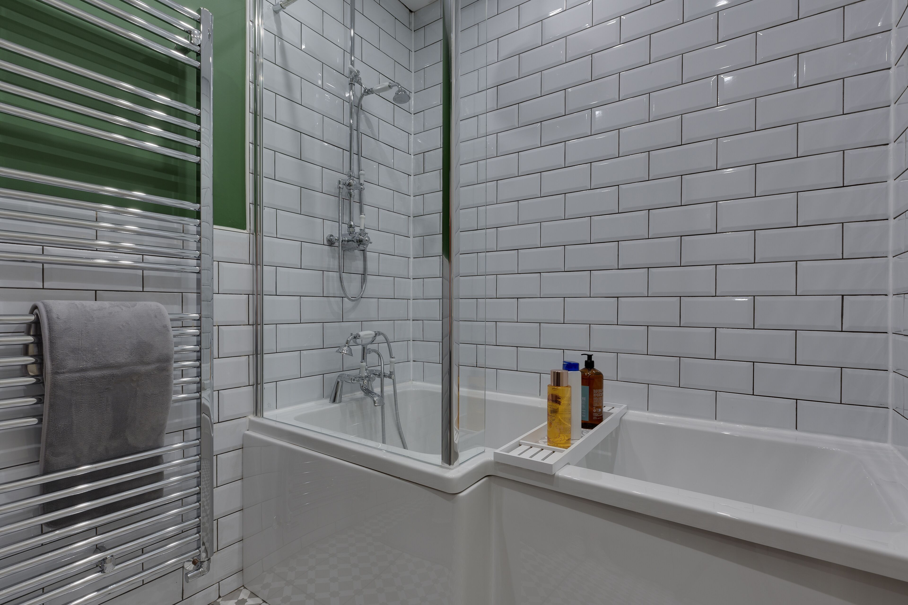 A modern bathroom with a glass-enclosed shower, a white bathtub, and a towel rack.