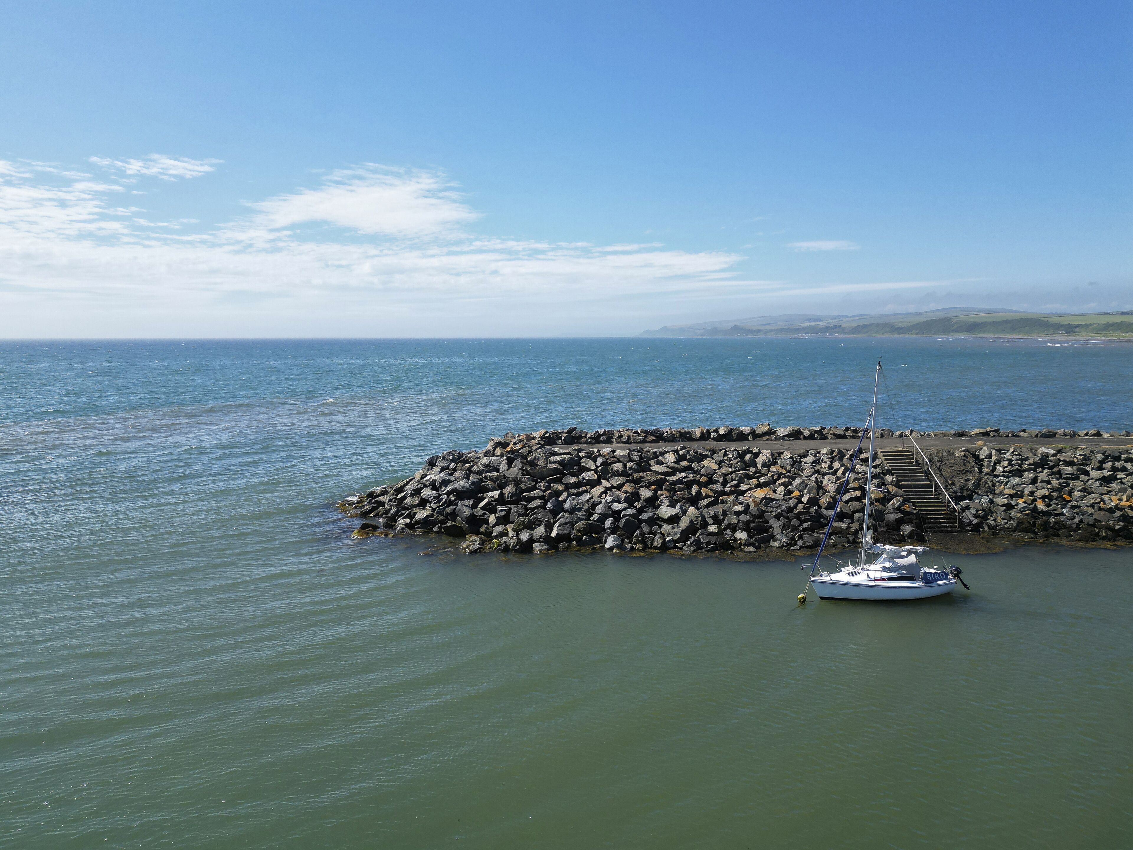A rocky pier with a boat docked at the end.