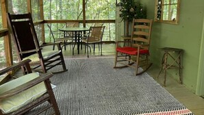 Een overdekt terras met houten meubels, een schommelstoel en een kerstboom.