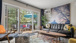 Ein modernes Wohnzimmer mit einem schwarzen Ledersofa, einem Holztisch und einem gemusterten Teppich.