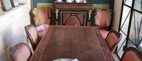 A traditional wooden dining table with six chairs, surrounded by a patterned rug and a decorative fireplace.