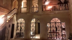 A building with arched windows and a balcony with a railing. - Riad Dar El Caid. Palais Siecle XIV (Tozeur)