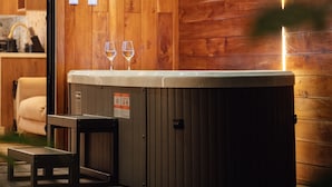 Un intérieur en bois avec un jacuzzi, deux verres et un banc.