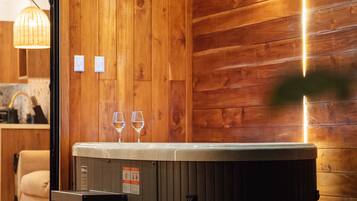 Un intérieur en bois avec un jacuzzi, deux verres et un banc.