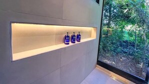 Une salle de bain avec une étagère intégrée où sont rangées trois bouteilles de gel hydroalcoolique.