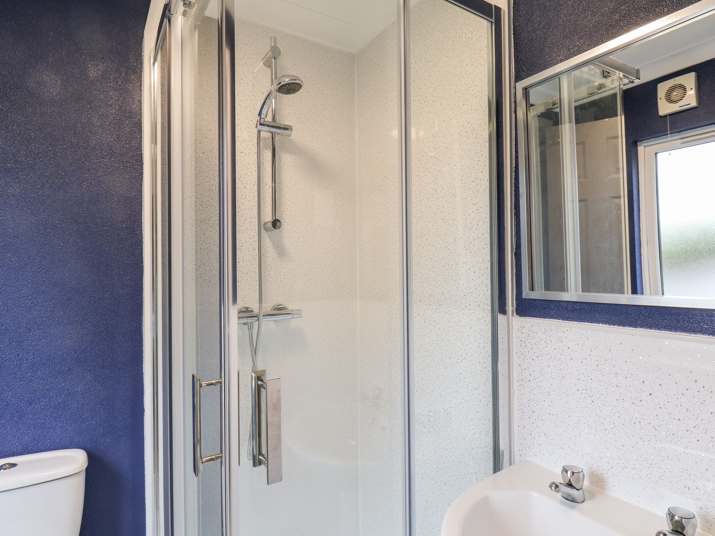 A modern bathroom with a glass-enclosed shower, a white sink, and a mirror above the sink.