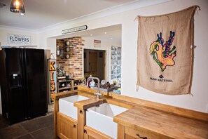 Welcome to the heart of the home, where a brick wall meets a spacious kitchen with a refrigerator, sink, and wooden cabinet.