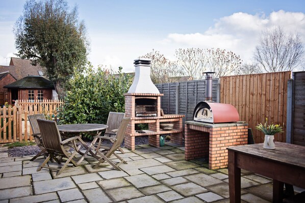 Enjoy al fresco dining with a brick barbecue grill and wood-fired pizza oven, surrounded by a comfortable seating area.