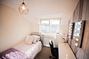 Cozy retreat with a single bed, desk, and vanity area.