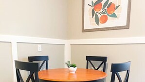 Une table à manger avec quatre chaises, une petite plante en pot et une œuvre d’art encadrée accrochée au mur.