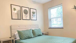 Une chambre à coucher bien rangée, avec un lit, deux oreillers, une table de chevet et une fenêtre.