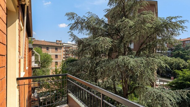 A balcony with a metal railing overlooking a residential area with trees and buildings. - A Casa di Giorgia by Wonderful Italy (Bologna)