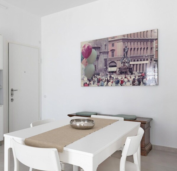 Un área de comedor con una mesa blanca, un cojín verde y un cuenco de metal.