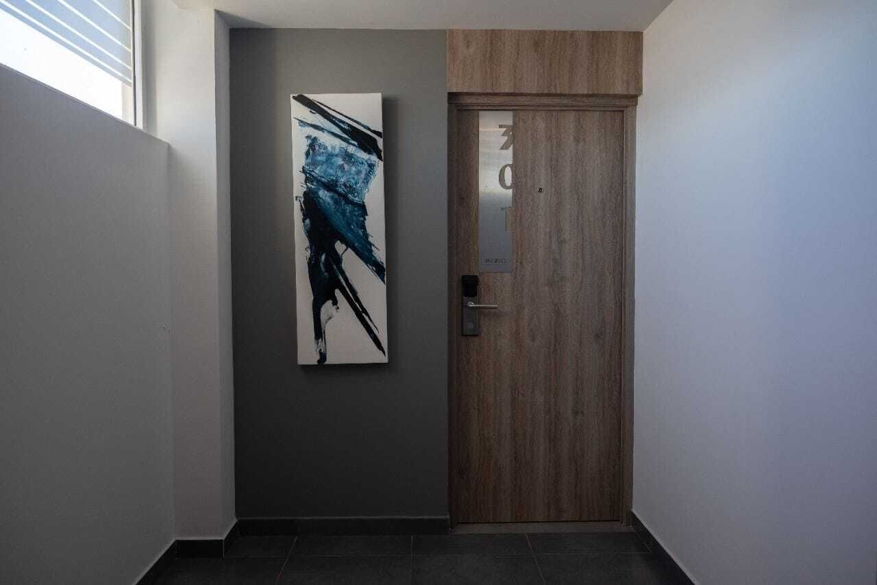 Um corredor com uma porta de madeira e uma pintura abstrata em preto e branco na parede.