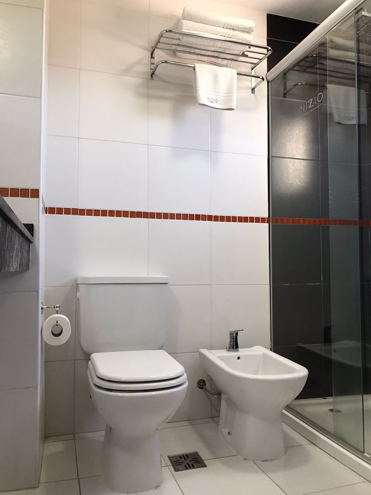 Un baño con inodoro, bidé y cabina de ducha de vidrio.