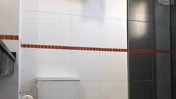 Un baño con inodoro, bidé y cabina de ducha de vidrio.