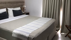 A hotel room with a large bed, a bedside table with a lamp, and a window with curtains. - Hotel Inizio (San Francisco)