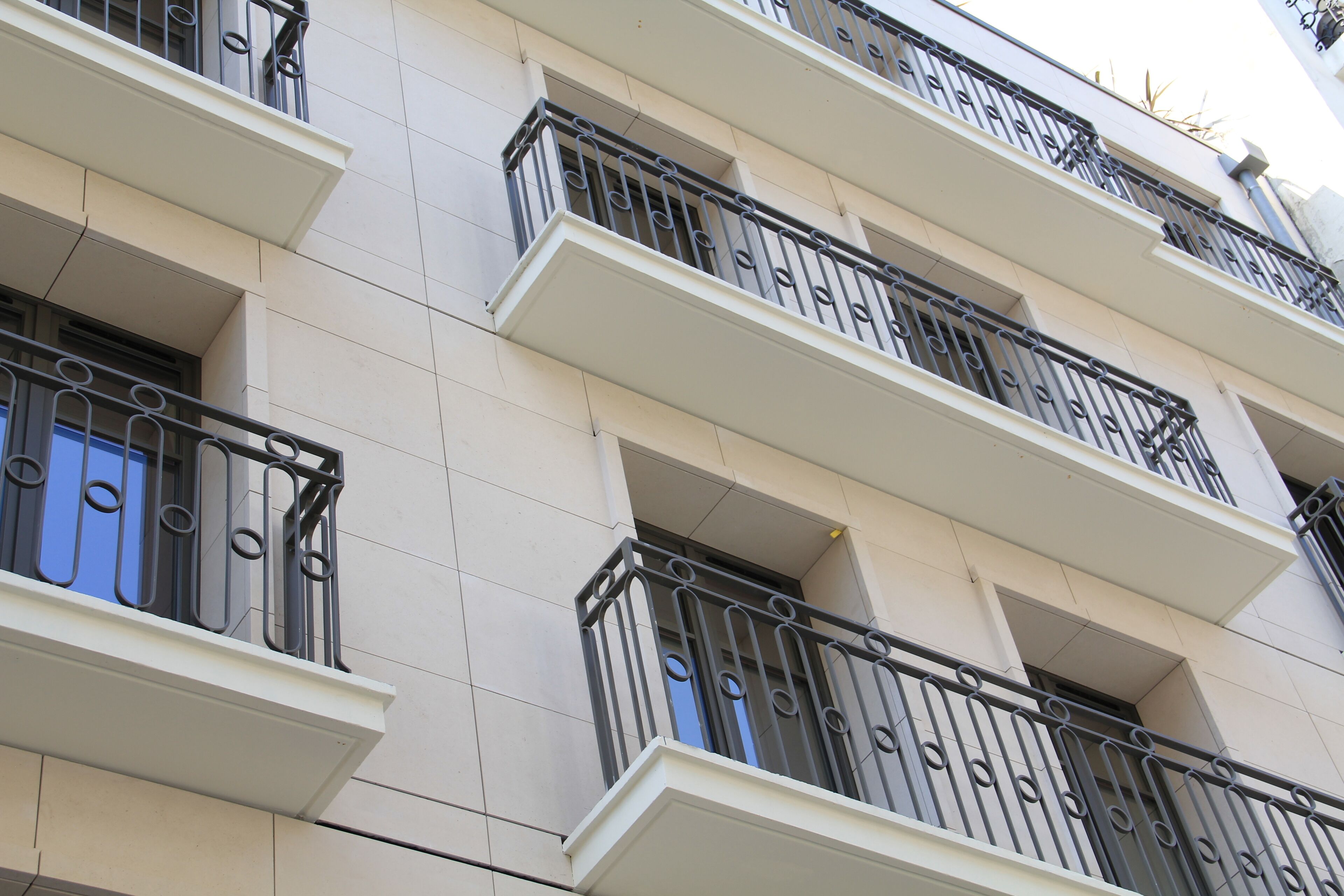 Un edificio de varios pisos con balcones y barandillas de hierro forjado negro.