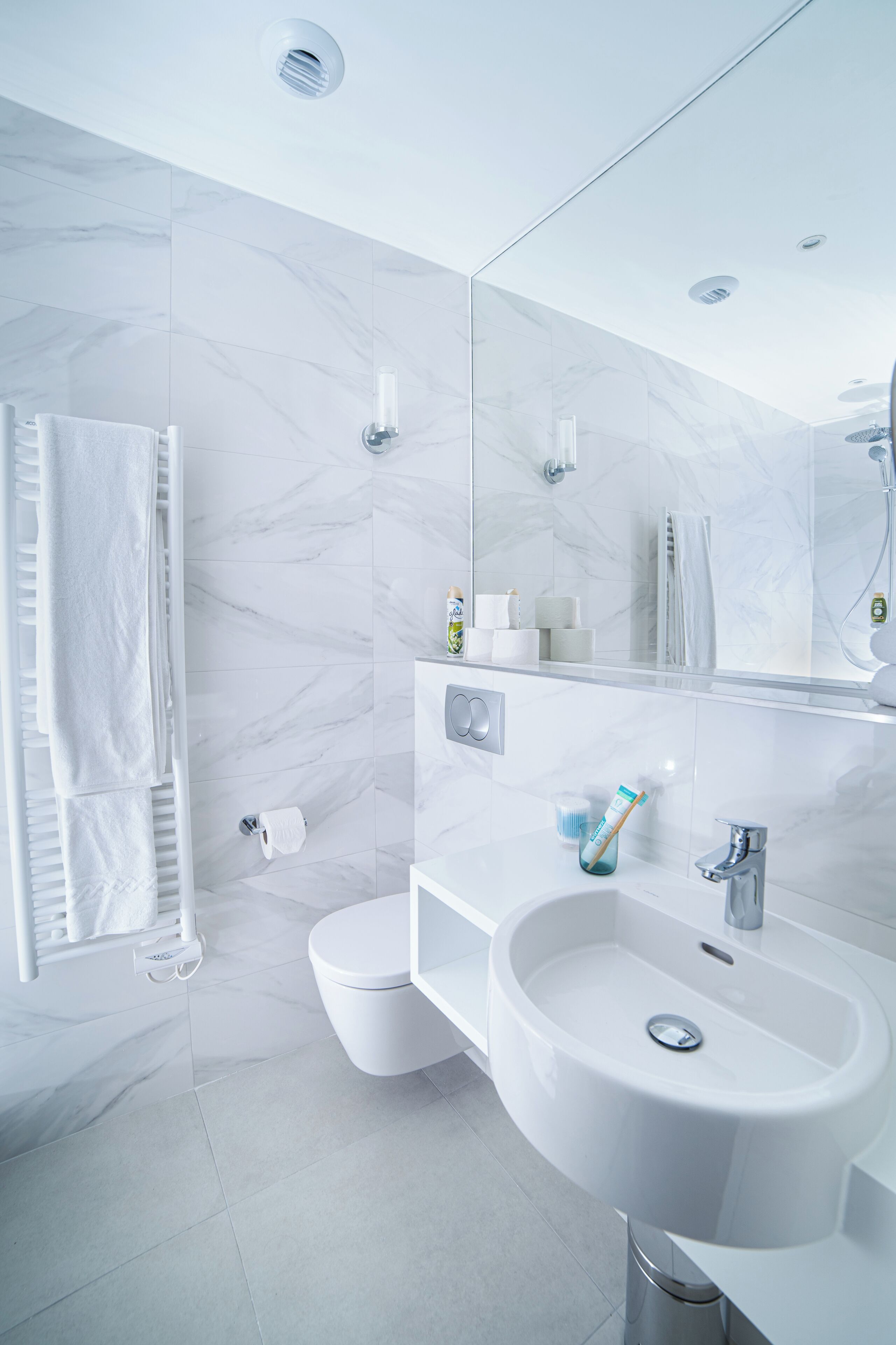 A modern bathroom with a white sink, mirror, and toilet.