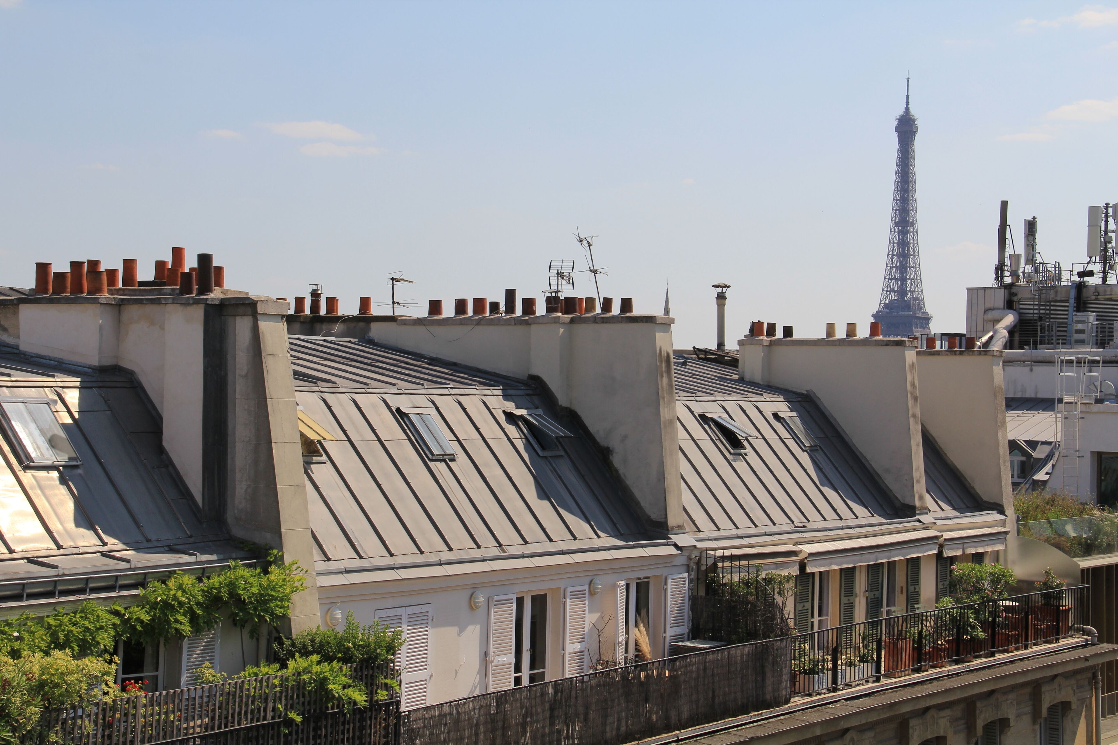 A row of residential buildings with sloped roofs and chimneys, featuring a view of the Eiffel Tower in the background.