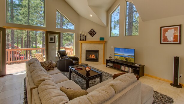 A spacious living room with a fireplace, large windows, and a balcony.