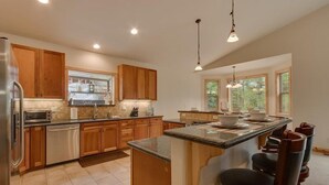 A modern kitchen with wooden cabinets, a central island, and pendant lighting.
