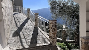 A stone staircase leading to a balcony with a metal railing, overlooking a mountainous landscape and a tree. - Vacation Home Paola Aurigo, relaxation, quiet and 16 km from the sea (Aurigo)