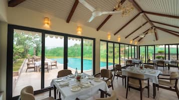 A dining area with tables set for service, overlooking a swimming pool.