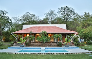 Una casa con techo rojo, piscina y jardín.