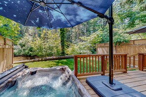 A hot tub with a wooden deck and a large umbrella providing shade. - Rare, dog-friendly riverfront retreat with hot tub access plus kayaks & AC (Tahuya)