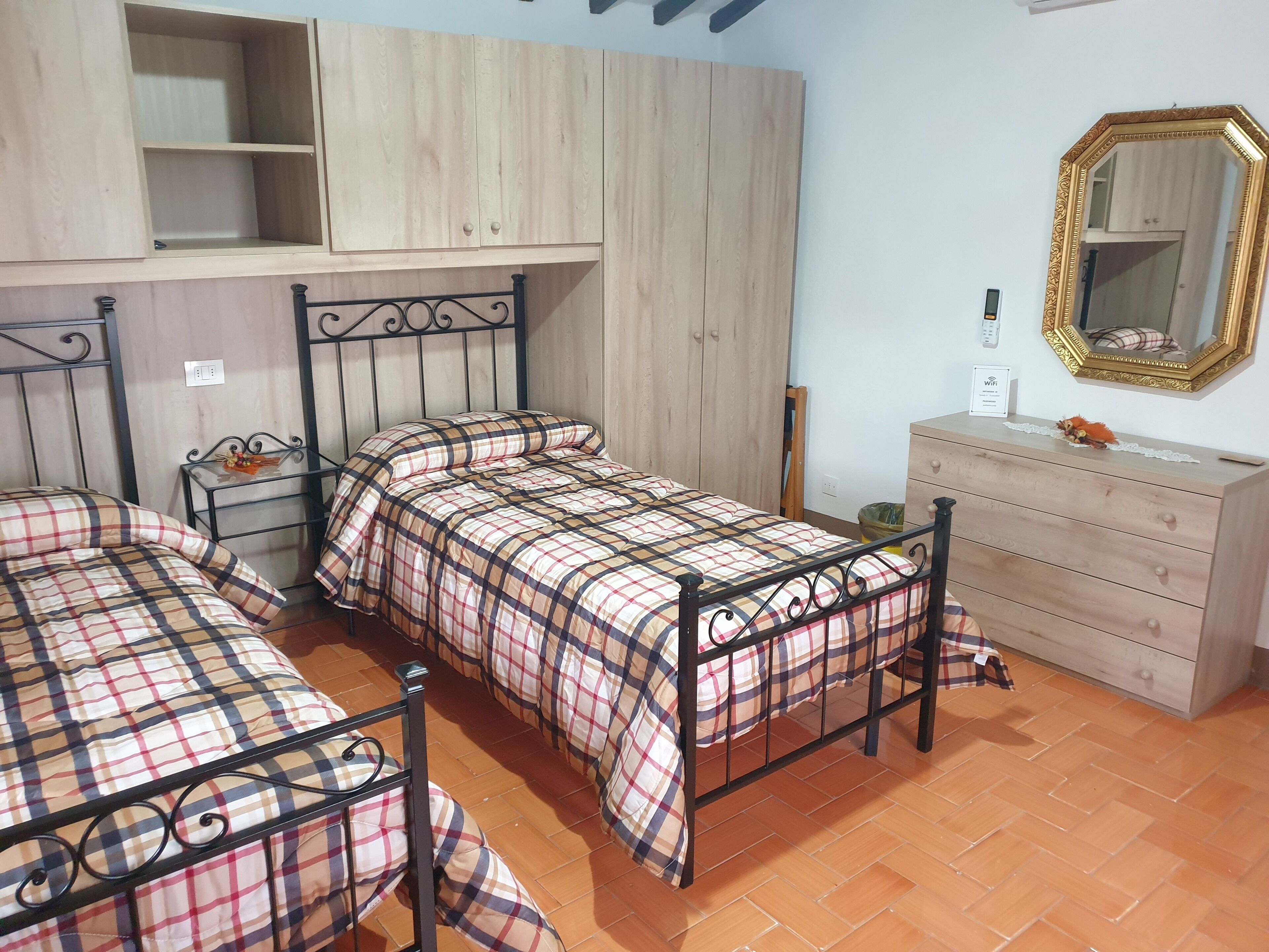 A room with two beds, a dresser, a mirror, and a wardrobe.