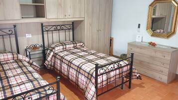 A room with two beds, a dresser, a mirror, and a wardrobe.