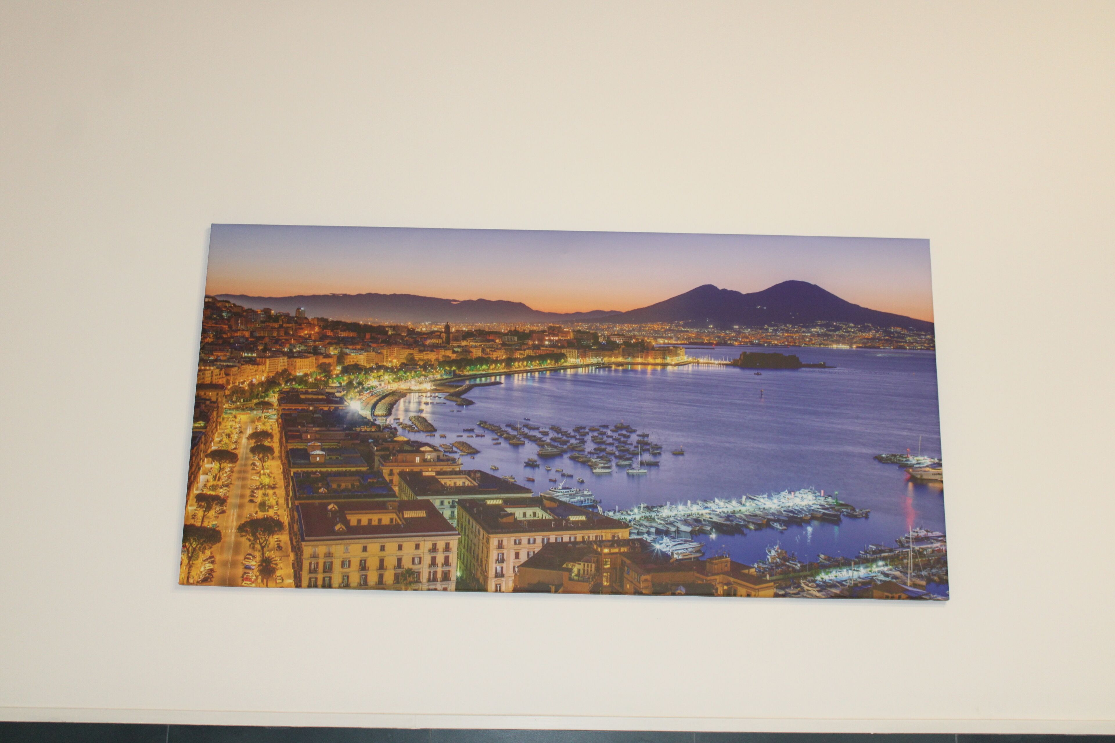 Une vue panoramique d’une ville côtière au crépuscule, avec une montagne imposante en arrière-plan.