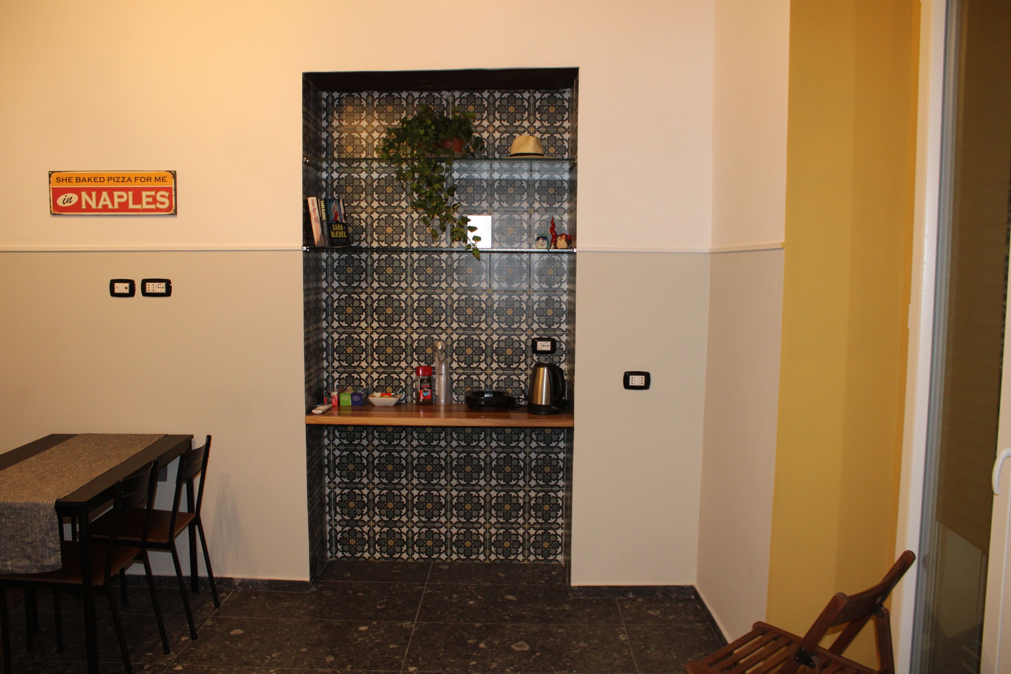 A compact kitchen with a patterned backsplash, a small countertop, and a dining area with a table and chairs.