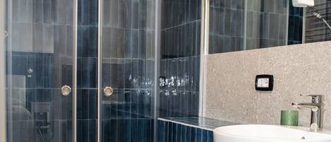A bathroom with a glass-enclosed shower, a white sink, and a toilet.