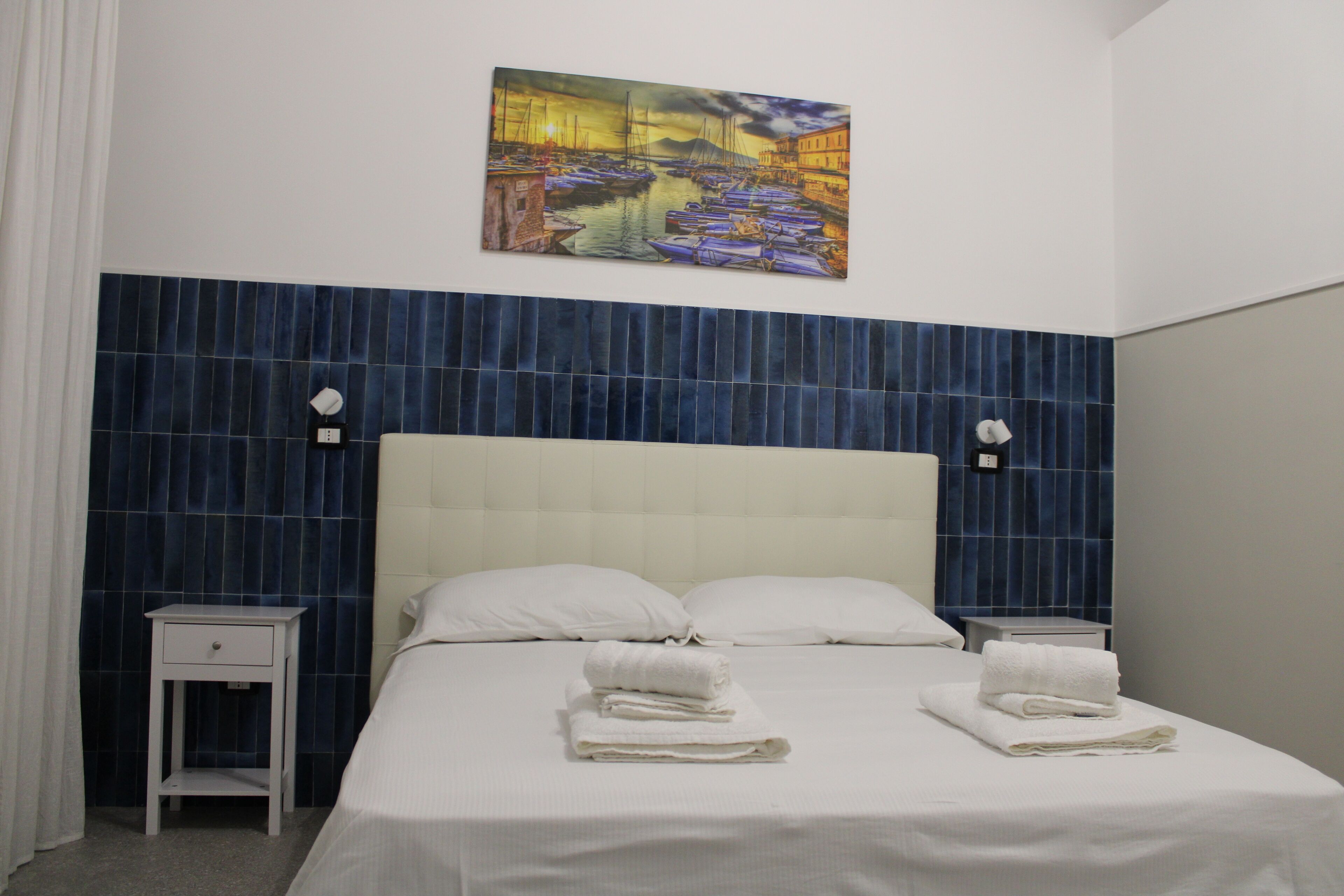 Una habitación de hotel con una cama, dos mesitas de noche y un cuadro en la pared.