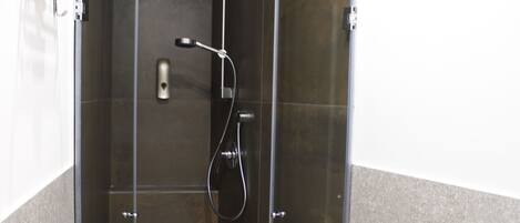 A modern bathroom with a glass-enclosed shower, a white toilet, and a towel rack.